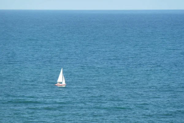 澄んだ空の下で青い海に浮かぶ帆船の空中ショット — ストック写真