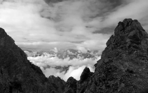 Серые Кадры Зазубренных Скалистых Вершин Гор Окруженных Облаками — стоковое фото