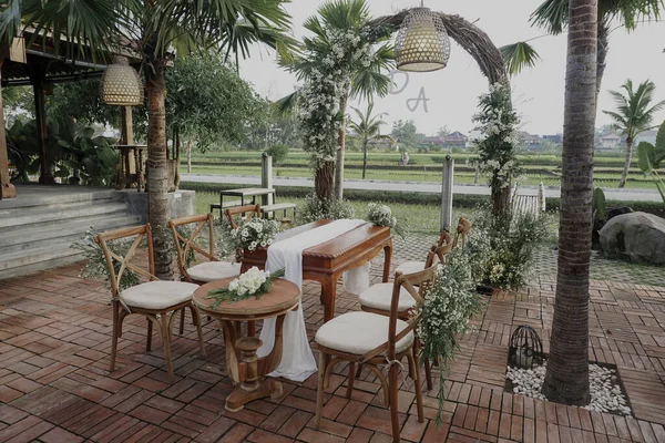An outdoor wedding design with tables, chairs and an arch with flowers