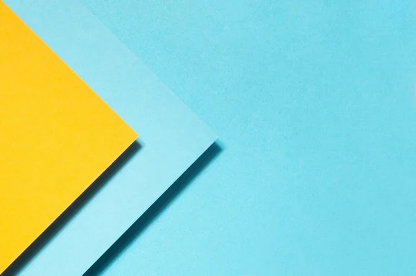 青い背景に幾何学的形状の黄色と青の紙の高角度ショット — ストック写真