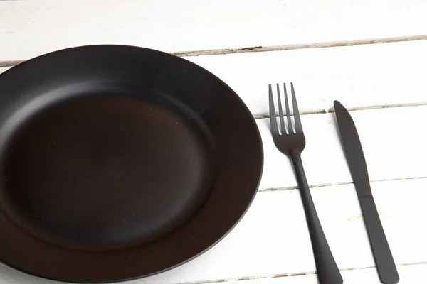 Nahaufnahme Eines Schwarzen Tellers Und Schwarzer Bestecke Auf Einem Holztisch — Stockfoto