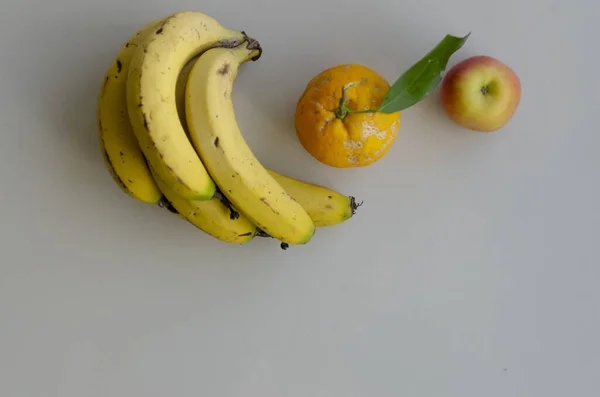 一粒扁平的成熟香蕉 桔子和苹果躺在灰蒙蒙的表面 — 图库照片