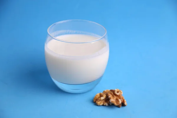 Närbild Skott Ett Glas Mjölk Bredvid Valnöt Blå Bakgrund Perfekt — Stockfoto