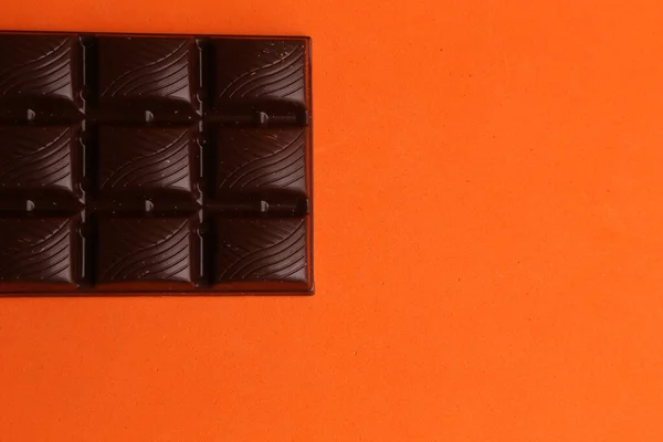 Nahaufnahme Einer Tafel Dunkler Schokolade Isoliert Auf Orangefarbenem Hintergrund — Stockfoto