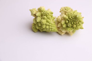 A closeups shot of two pieces of fresh romanesco broccoli on a white surface clipart