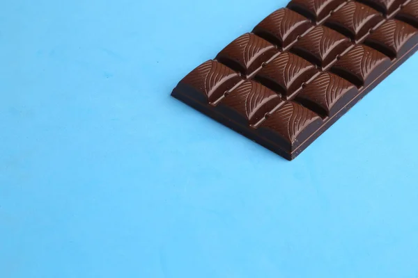 Uma Barra Texturizada Chocolate Escuro Uma Superfície Azul — Fotografia de Stock