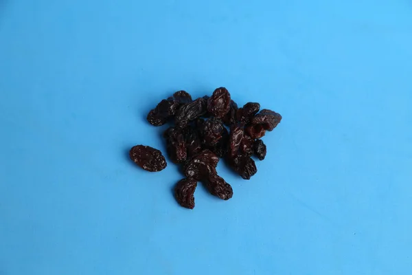 Eine Nahaufnahme Schwarzer Rosinen Auf Blauem Hintergrund — Stockfoto