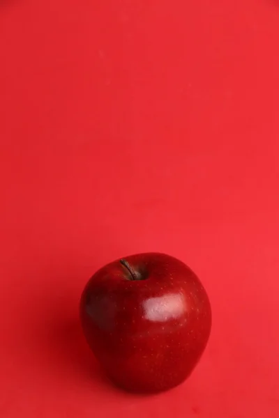 Pionowe Selektywne Ujęcie Ostrości Świeżego Czerwonego Jabłka Odizolowanego Czerwonym Tle — Zdjęcie stockowe