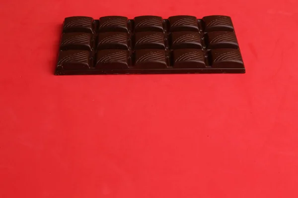 Eine Hochwinkelaufnahme Einer Ganzen Schokoladentablette Auf Einer Roten Oberfläche — Stockfoto