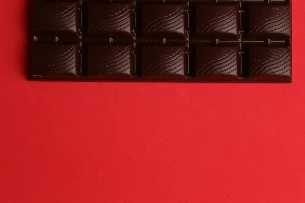 Высокоугольный Снимок Плитки Тёмного Шоколада Изолированной Красной Поверхности — стоковое фото