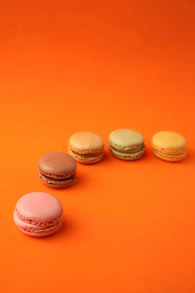 Eine Vertikale Aufnahme Bunter Macarons Auf Orangefarbenem Hintergrund — Stockfoto