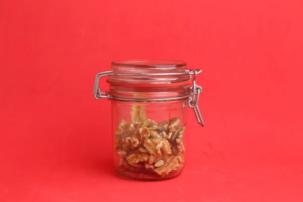 Las Deliciosas Nueces Frasco Vidrio Sobre Fondo Rojo — Foto de Stock