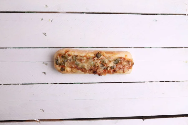 一张特写镜头 是一只美味的热狗 背景是木制的奶酪和胡椒 — 图库照片