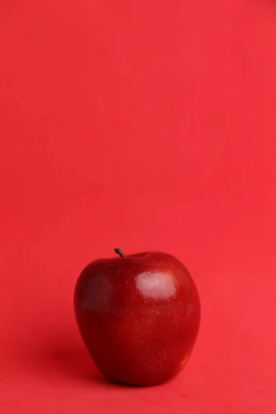 Вертикальный Снимок Целого Красного Яблока Красном Фоне — стоковое фото