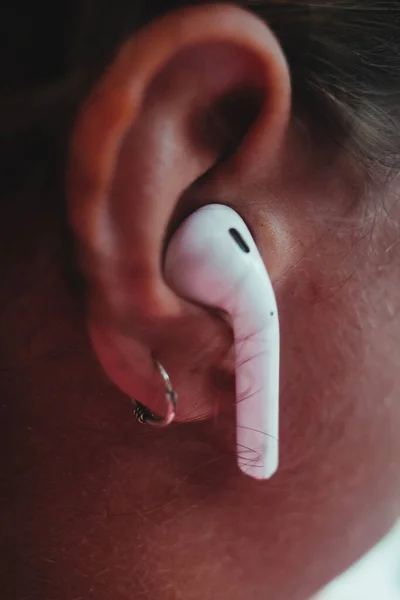 女性の耳に無線ヘッドフォンの垂直クローズアップショット — ストック写真