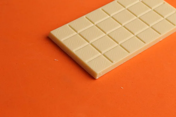 Tiro Alto Ângulo Uma Barra Chocolate Branco Uma Mesa Laranja — Fotografia de Stock