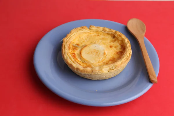 一个美味的自制奶酪派放在盘子里 盘子里有一个红色背景的木制勺子 — 图库照片