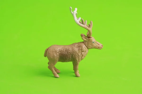 Een Closeup Van Een Plastic Rendier Speelgoed Een Groene Achtergrond — Stockfoto
