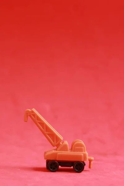 Pionowe Ujęcie Małego Plastikowego Żurawia Zabawki Czerwonym Tle — Zdjęcie stockowe