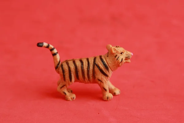 在红色背景上隔离的老虎形塑料玩具特写 — 图库照片