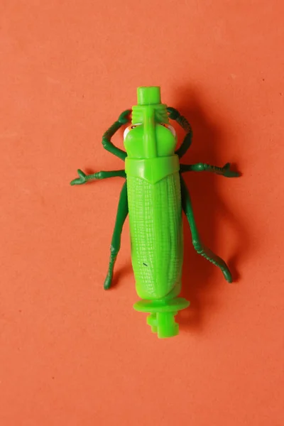 Närbild Grön Plast Gräshoppa Leksak Orange Bakgrund — Stockfoto