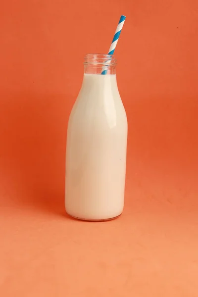 Вертикальный Снимок Бутылки Молока Соломинкой Оранжевом Фоне — стоковое фото