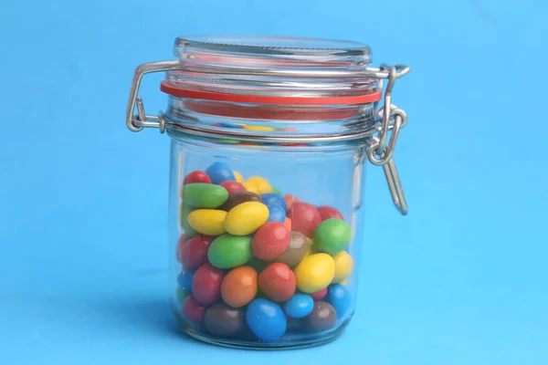 Closeup Shot Colorful Chocolate Balls Jar Isolated Blue Background — Stock Photo, Image