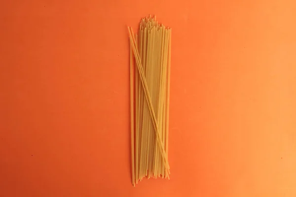 Eine Draufsicht Auf Einen Haufen Roher Spaghetti Auf Orangefarbener Oberfläche — Stockfoto