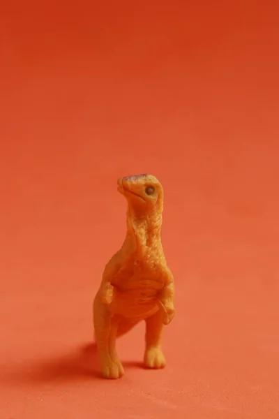 Вертикальний Знімок Гумової Іграшки Динозавра Ізольовано Гладкому Червоному Тлі — стокове фото