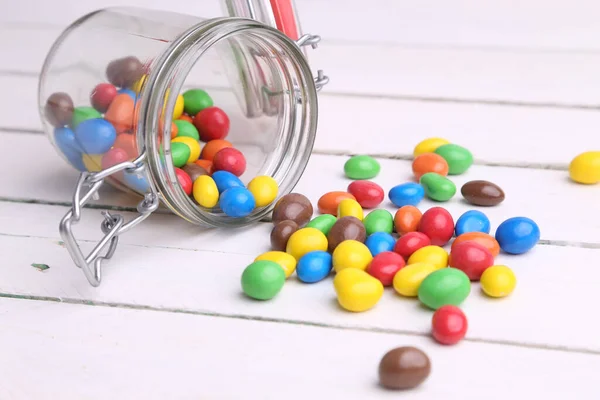 Closeup Shot Colorful Candies Pouring Glass Jar Wooden Table — Stock Photo, Image