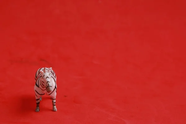 Крупный План Пластиковой Игрушки Форме Зебры Красном Фоне — стоковое фото