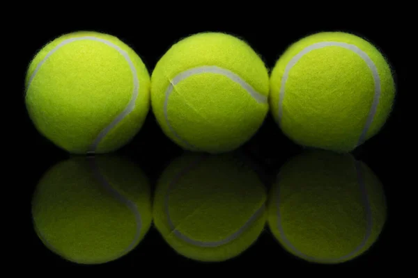 反射する黒い表面に3つのテニスボールの反射のクローズアップショット — ストック写真