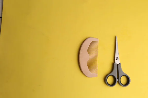 黄色表面上的一把木制梳子和一把剪刀 — 图库照片