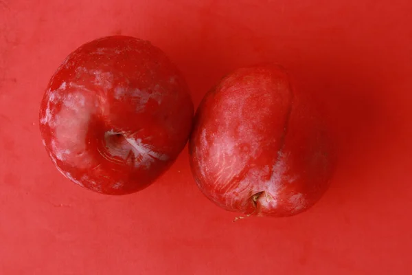 Primer Plano Dos Ciruelas Rojas Sobre Fondo Rojo —  Fotos de Stock