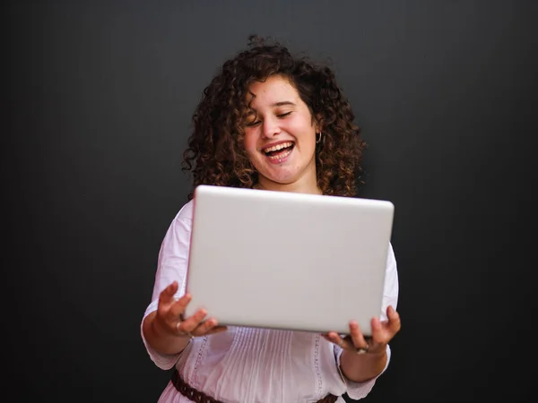 一个快乐的白人女人在黑暗的背景下使用她的笔记本电脑 — 图库照片