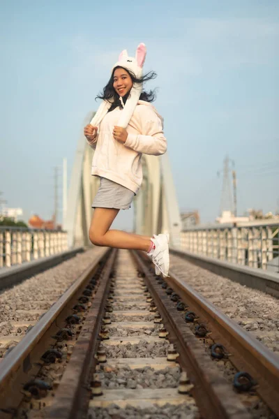 一张亚洲女人头戴一顶在铁轨上的滑稽帽子的纵向照片 — 图库照片