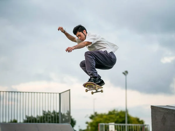 スケートパークでスケートボードとトリックをやっている若い白人男性 — ストック写真