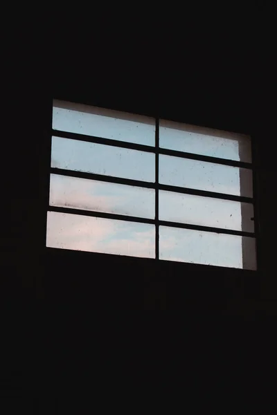 Вертикальный Снимок Неба Через Грязное Окно Темной Комнаты — стоковое фото