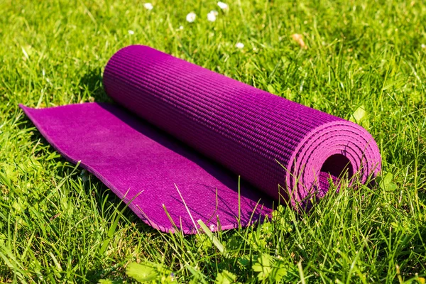 Высокоугольный Снимок Свернутого Фиолетового Коврика Йоги Покрытом Травой Лугу — стоковое фото