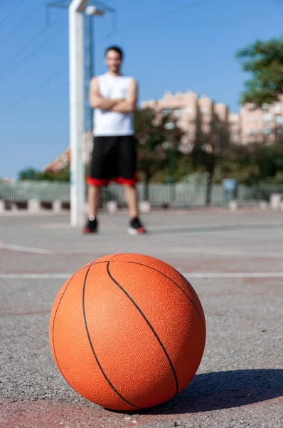 裁判所と背景の人のバスケットボールボールの垂直選択的フォーカスショット — ストック写真