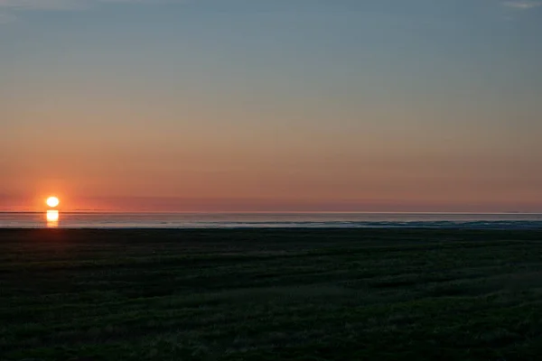 Ein Farbenfroher Sonnenuntergang Über Einem Lebhaft Grünen Rasen Und Meer — Stockfoto