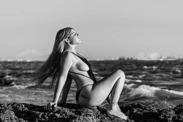 スペイン カディスのラ カレタビーチの海辺でリラックスしたタトゥーのある女性のグレースケールショット — ストック写真