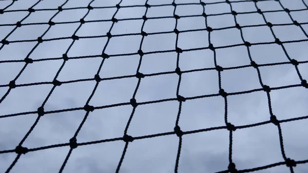 灰色の曇り空の背景に黒いネットのクローズアップショット — ストック写真