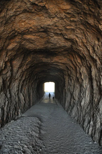 Вертикальный Снимок Каменистого Туннеля Идущего Пляж — стоковое фото