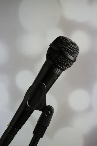 Vertical Shot Person Holding Black Microphone Grey Background White Bokeh — Stock Photo, Image