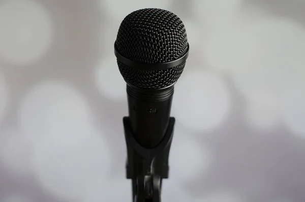 Uma Pessoa Segurando Microfone Preto Fundo Cinza Com Luzes Bokeh — Fotografia de Stock