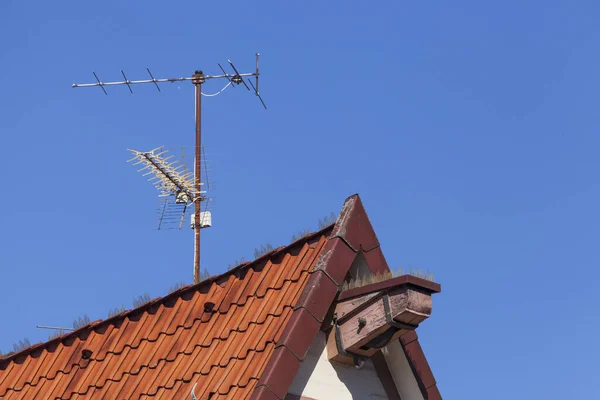 青い空の背景にアンテナを持つ家の屋根のローアングルショット — ストック写真