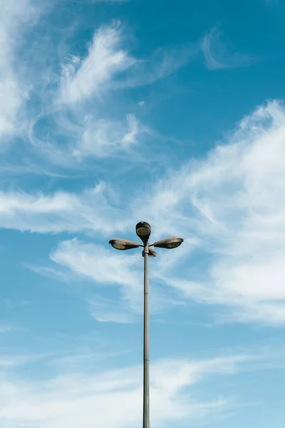 ポルトガルのリスボンの曇った空に対して4発の丸い球根を持つランプポストの垂直ショット — ストック写真