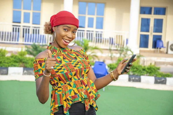 一个年轻漂亮的非洲女人笑着在外面用她的手机 — 图库照片