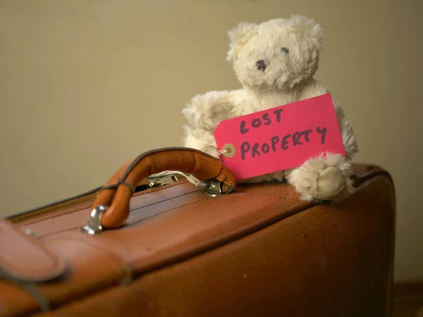 A bear toy on an old suitcase with a \